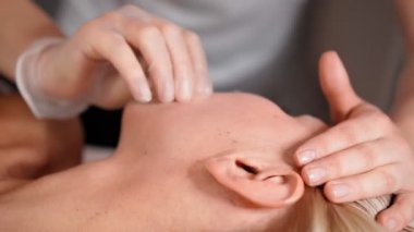 Kadın masör, genç ve güzel bayan müşteri sarışına yüz masajı ve ağız boşluğu yapar. Güzellik salonunda mükemmel cilt bakımı. Kozmetik servisi. Sağlık ve İlaç Hizmetleri