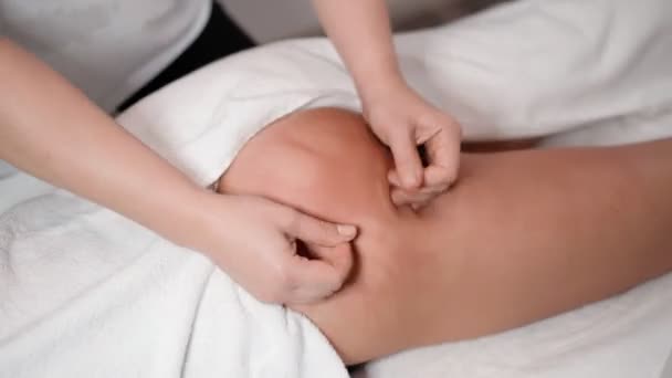 Uma massagista mulher faz uma poderosa massagem anti-celulite das nádegas para uma cliente feminina em uma clínica estética. Conceito de cuidados com a pele. Saúde e medicina. Close-up — Vídeo de Stock