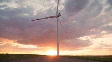 Yel değirmeni, güzel bir günbatımı gökyüzünün arka planında dönüyor. Yeşil ekolojik dünya için yenilenebilir enerji üretimi. Alternatif enerji kavramı. Rüzgar santrali. Yavaş çekim.