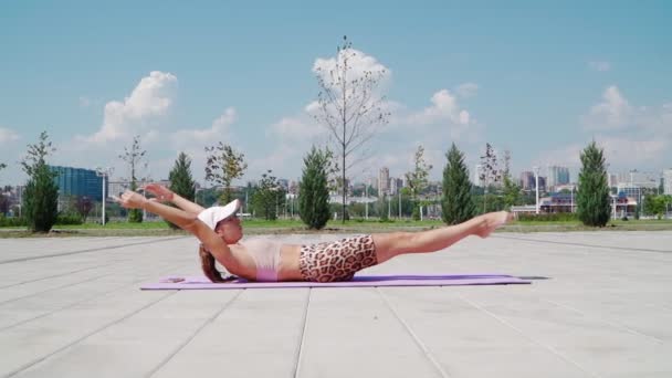 穿着运动服的女运动员正在给腹部抽水 瘦小的女人正在城市公园里做腹肌锻炼 健康的生活方式 户外运动的概念 慢动作 — 图库视频影像