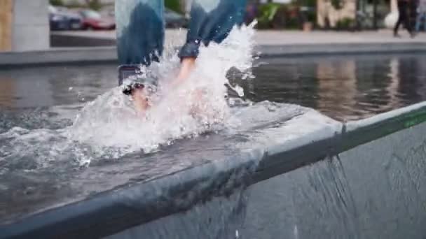 ジーンズ姿の孤独な男が街の公園で裸足で水の上を歩いている 近くでゆっくりとした動き — ストック動画