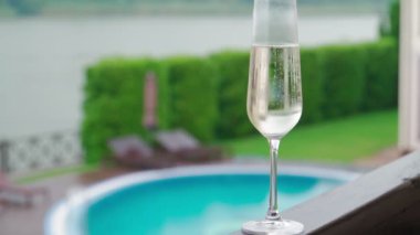 Tatil sırasında lüks bir otelde havuz kenarında beyaz şampanya ya da Prosecco bardağı. Yakın plan. İçecekleri tazeliyorum. Yavaş çekim.