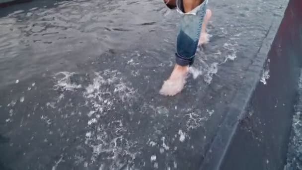 一个穿着破牛仔裤的孤独男子赤脚在城市公园的水面上行走 慢动作 — 图库视频影像