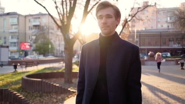 Serious handsome business man walks after work in the sunset light of the city. — Stock Video