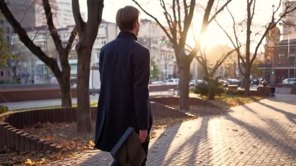 Serious handsome business man walks after work in the sunset light of the city. — Stock Video