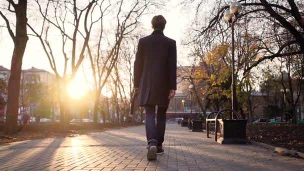 Ernstige knappe zakenman loopt na het werk in de zonsondergang licht van de stad. — Stockvideo