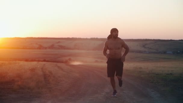 Sakallı, kaslı, atletik bir Arap güzel bir günbatımı arka planında koşuyor.. — Stok video