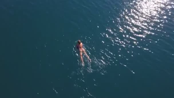 Légi felvétel. gyönyörű nő vékony alak fürdőruhában úszik a kristálytengerben — Stock videók