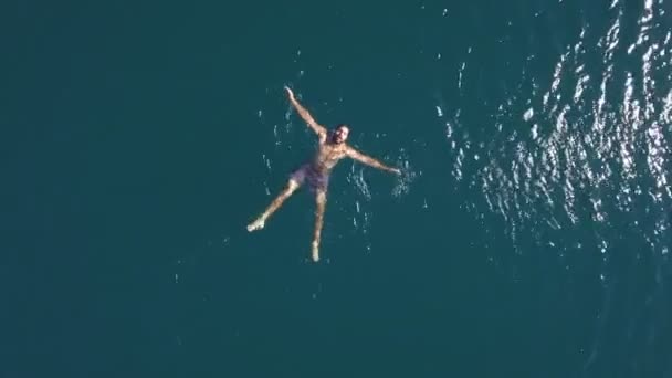 Vista aérea. hombre musculoso se encuentra la superficie de agua de mar cristalina. Vacaciones de verano — Vídeos de Stock
