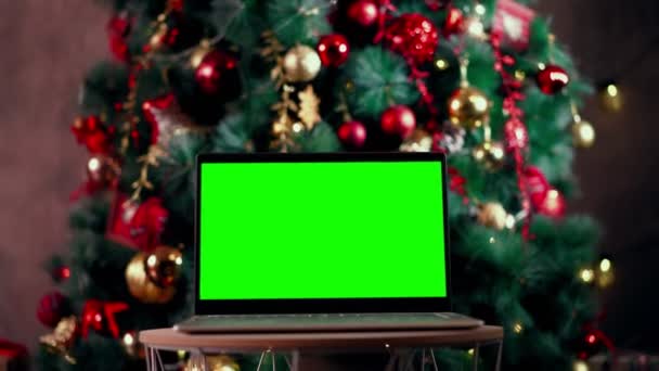 Modern chroma key green screen laptop computer against background christmas tree — Stock Video