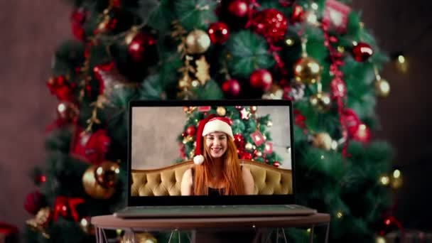 Woman with in santa hat sits in splits holds out New Years gift via a laptop — Stock Video