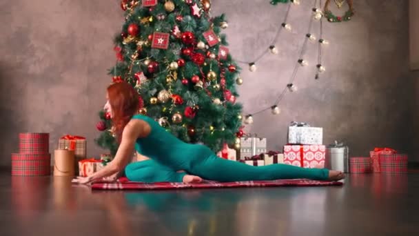 Slanke vrouw oefent yoga achtergrond kerstboom. Gewichtsverlies na Nieuwjaar — Stockvideo