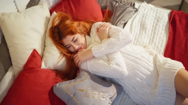 Cozy sexy red-haired woman in white knitted sweater lies on sofa. Happy New Year — Stock Video