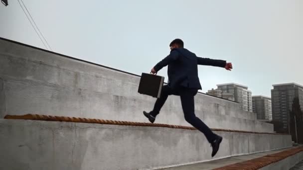 El hombre de negocios con traje salta parapetos. Concepto escaleras de carrera Promoción corporativa — Vídeos de Stock
