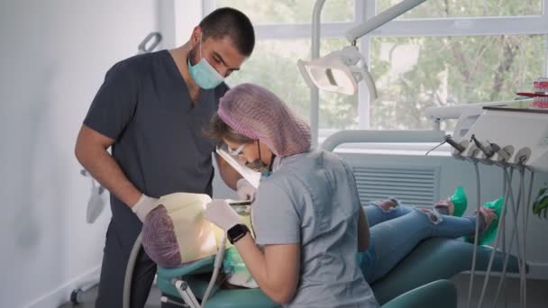 Kobieta Dentysta Ochronnej Tarczy Masce Twarzy Pomocą Asystenta Męskiego Sprzętu — Wideo stockowe