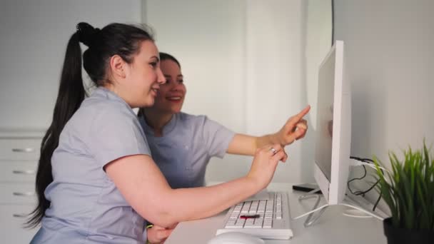 Two Young Beautiful Female Doctors Discussing Treatment Plan Sitting Computer — Stock Video