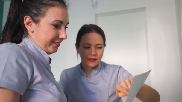 Two Young Beautiful Female Doctors Smiles Discussing Treatment Plan Sitting — Stock Video