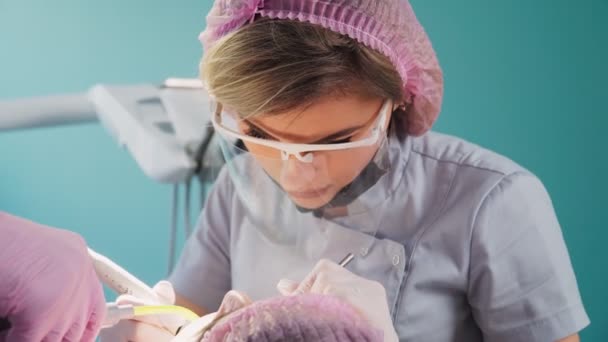 Vacker Kvinnlig Tandläkare Ett Skyddande Sköld Och Ansiktsmask Med Hjälp — Stockvideo
