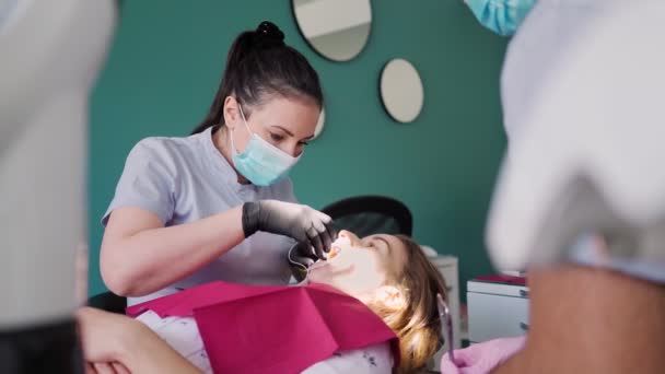 若い女性歯科医は 患者の歯を検査し 歯科室で働く ブレースの設置 医療と医学の概念 スローモーション — ストック動画