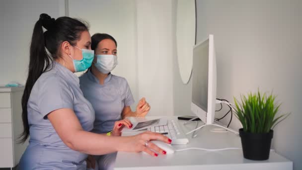 Duas Jovens Médicas Bonitas Máscaras Protetoras Discutindo Plano Tratamento Sentadas — Vídeo de Stock