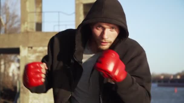 Junge Boxer mit roten Boxhandschuhen beim Training im Freien. Üben Sie Schattenboxen. Zeitlupe. — Stockvideo