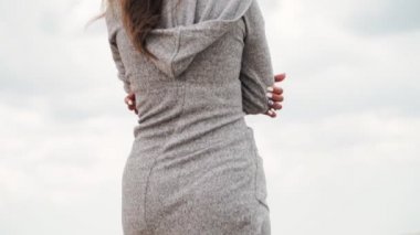 Gri kapüşonlu kazaklı yalnız kız kıyıdaki deniz boyunca gider. Ağır çekim. Yakın plan..