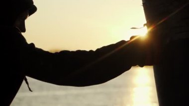 Ağır çekim. Boksör trenleri kum torbasına çarpar. Güzel bir günbatımı arka planında destansı bir çerçeve