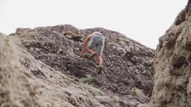 Gövdesine kadar çıplak olan atletik adam kayaya tırmanıyor. Ağır çekim. Alt açı. — Stok video