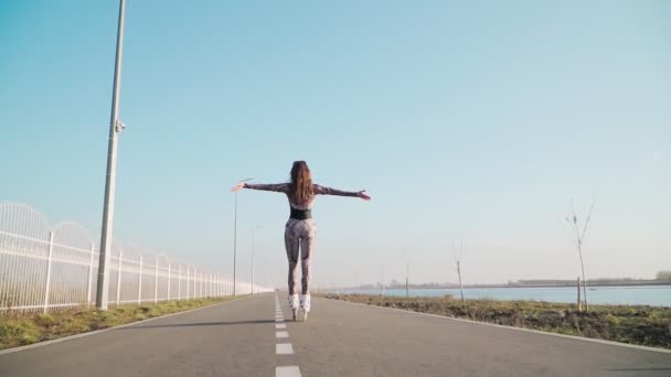 Atletický Slim Rides Girl Roller bruslení a šťastně zvedne ruce. mladá žena si užívá života — Stock video