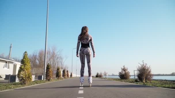 Athletic Slim Rides Дівчина катається на ковзанах по шляху на тлі красивого озера . — стокове відео