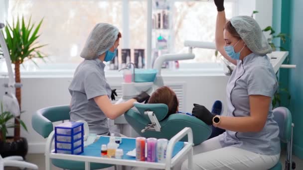 Deux femmes médecins dans une clinique dentaire, servent le patient petit garçon. Dentiste de travail — Video