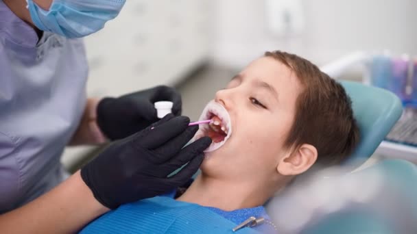 Žena lékař v zubní klinice sloužit pacientovi malý chlapec s poškozeným dítětem zuby. — Stock video
