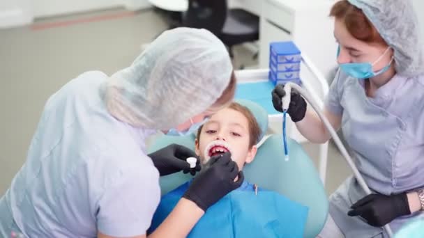 Dwie kobiety Lekarze w czapce lekarskiej w klinice stomatologicznej, służyć pacjentowi Little Boy — Wideo stockowe