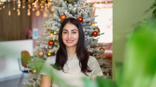 Hermosa sonrisa mixta mujer de raza cara bonita en el árbol de Navidad de fondo — Vídeo de stock