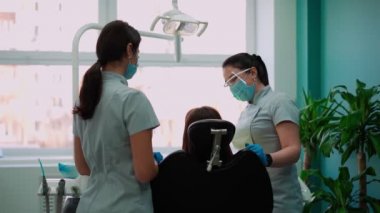 Diş Kliniğinde Maskeli İki Kadın Doktor Kadın Hasta 'ya hizmet ediyor. Çalışma Dişçisi