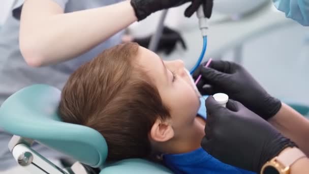 Två kvinnliga läkare i sjukhytten på tandvårdskliniken, betjäna den tålmodig lilla pojken — Stockvideo