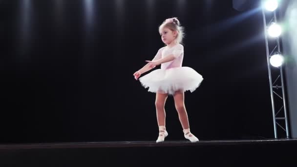 Niña bailarina de aspecto caucásico en un tutú rosa baila en el escenario. Niños. Movimiento lento. — Vídeo de stock