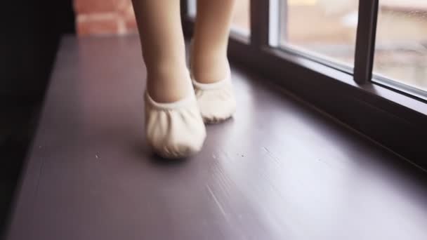 バレエのアパートの小さな赤ん坊の足は窓辺に沿って行く。スローモーション。スタジアムでの銃撃戦 — ストック動画