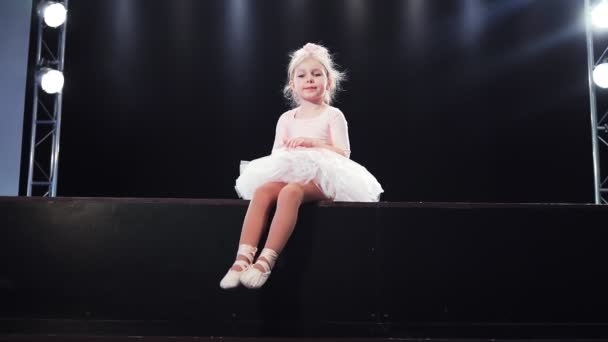 Mooie kleine baby meisje ballerina in roze tutu zitten op het podium. Kinderballet. Langzame beweging — Stockvideo