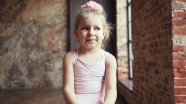 Sandalyeye oturmuş gülümseyen güzel sarışın kız çocuğu. Yavaş çekim.