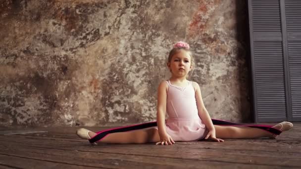Девочка-гимнастка, сидящая в кустах. Детский спорт. Маленькая блондинка. Медленное движение. — стоковое видео