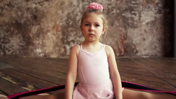 Ung flicka gymnast sitter i splittringar. Barnens sport. Lilla blondin. Långsamma rörelser. — Stockvideo