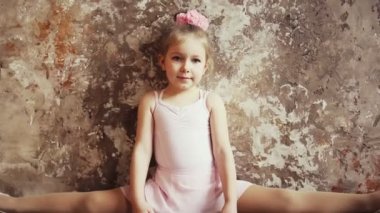 Küçük kız jimnastikçi, dağlarda oturuyor ve gülümsüyor. Çocuk sporları. Sarışın Bebek.