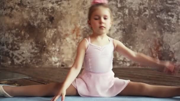 Gimnastyczka, siedząca w rozłące i rozgrzewająca się. sporty dla dzieci. Blondynka. — Wideo stockowe