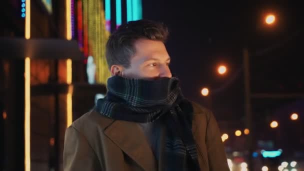 Człowiek zamrażanie z zimna stojąc w pobliżu jezdni i centrum handlowego w nocy — Wideo stockowe