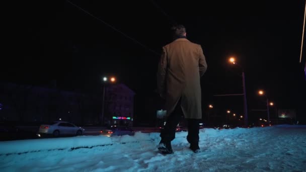 Happy smiling successful man walks on winter night along street glowing city. — Stock Video