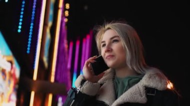 Kış gecesi cep telefonuyla konuşan kız Parlak Parlak Alışveriş Merkezi 'nin yakınında