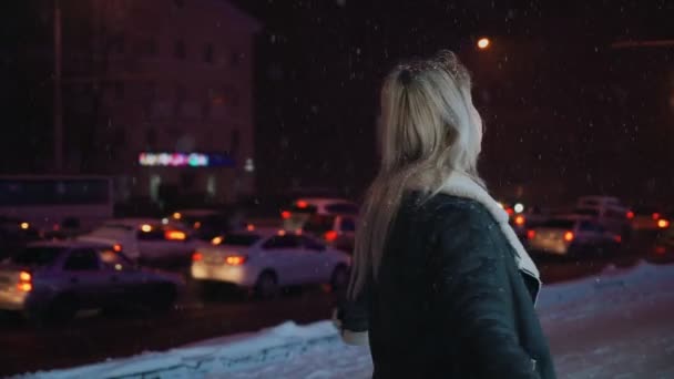 Girl Spinning with Happiness on winter night snowfall glowing shopping center — Stock Video