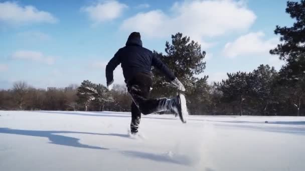 Glücklicher Mann läuft im Schnee und stürzt sich komisch. Fröhlicher Kerl mit Spaß auf verschneiter Lichtung — Stockvideo