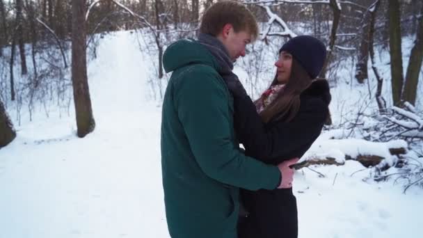 Milenci stojí a objímají se v Zimním lese. Krásný muž a žena v objetí — Stock video